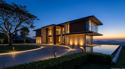 Hillside villa exterior at pre-dawn blue hour with soft amber façade graze and warm foyer glow visible through the glass entrance.