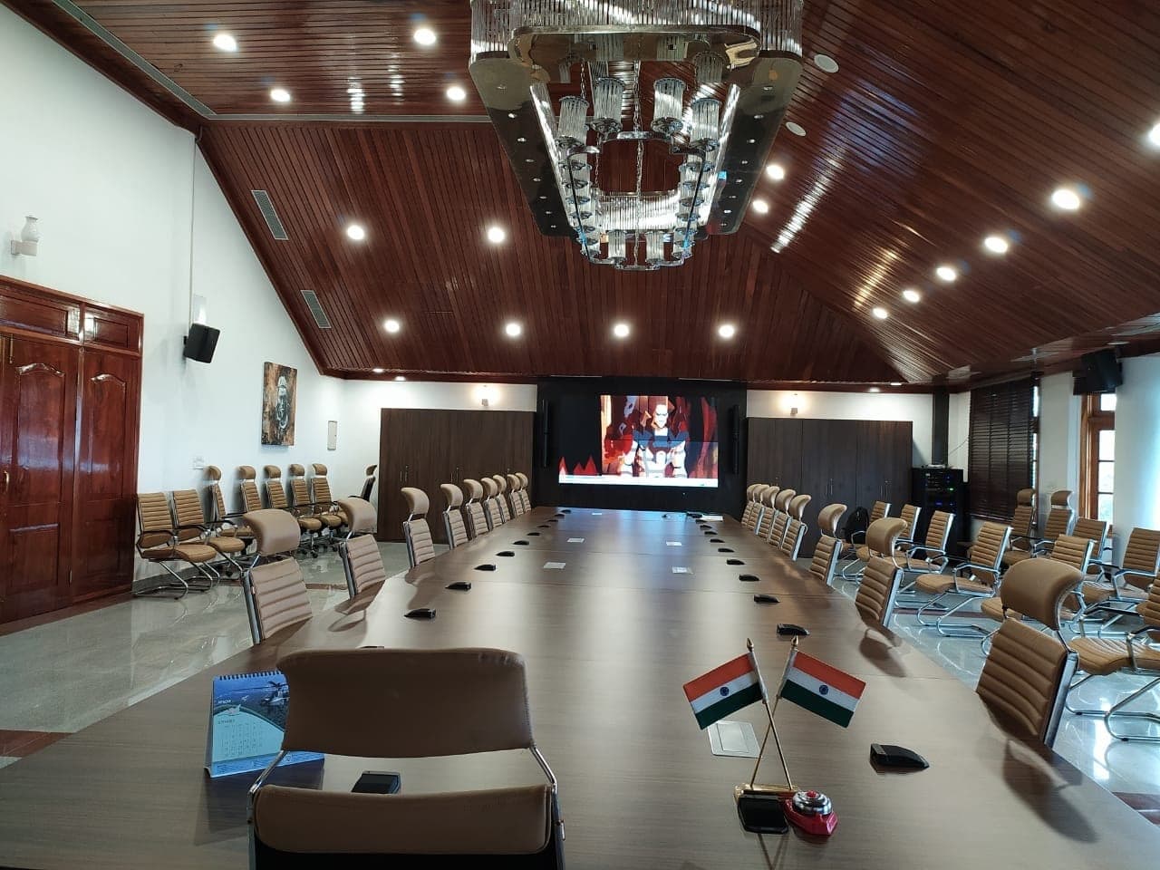 Executive conference room at the Chief Minister's Residential Complex, Kohima — wide view under the timber vaulted ceiling with the Indian flags on the table.