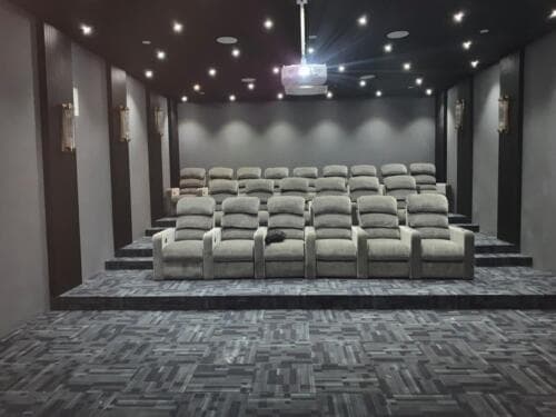 Premium home theatre Itanagar — gray recliners, vertical acoustic wall panels, decorative sconces