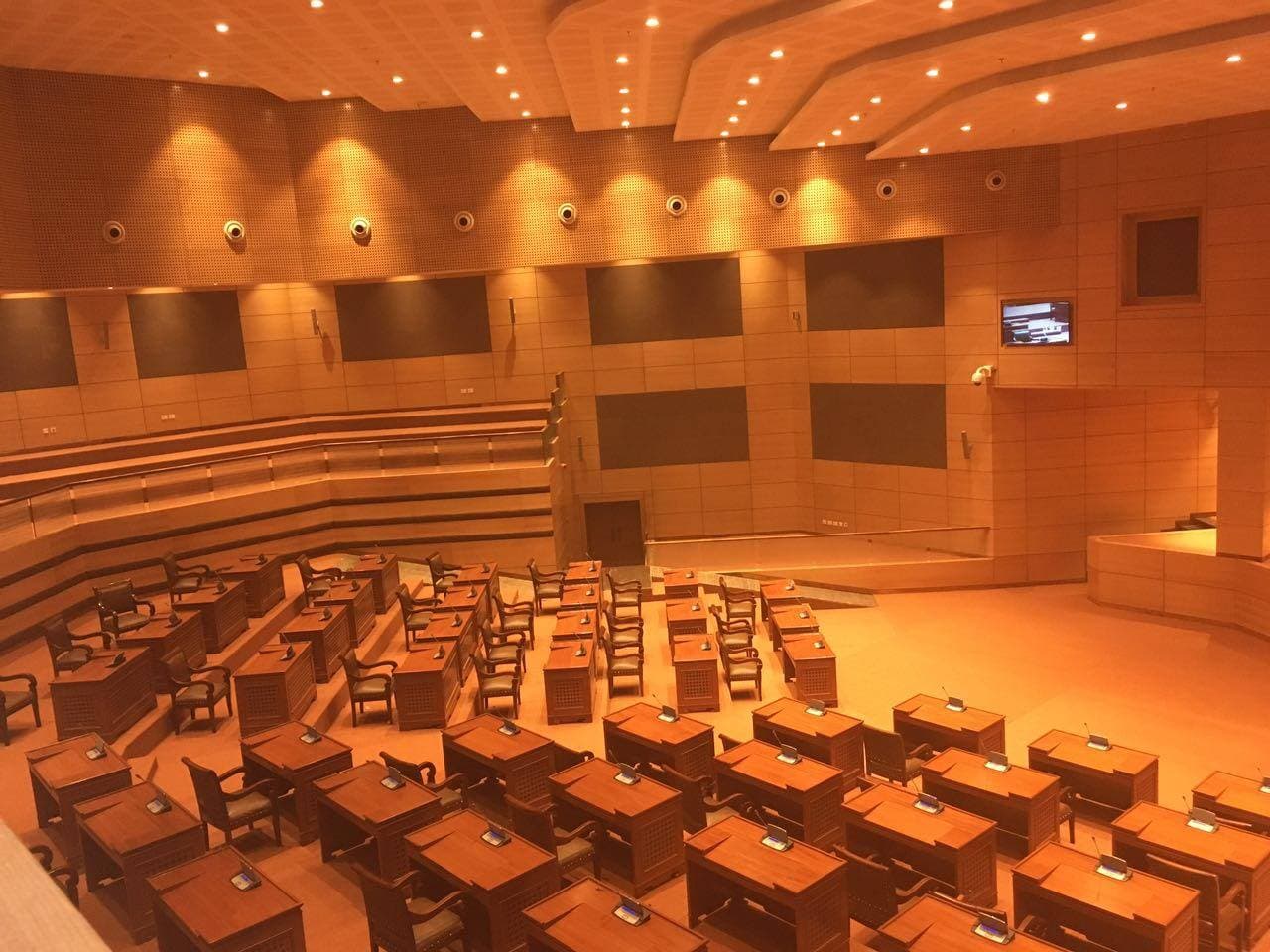 Assembly chamber in recess — house lights dimmed, only the warm amber cove lighting visible.