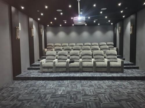 Premium home theatre Itanagar — gray recliners, vertical acoustic wall panels, decorative sconces